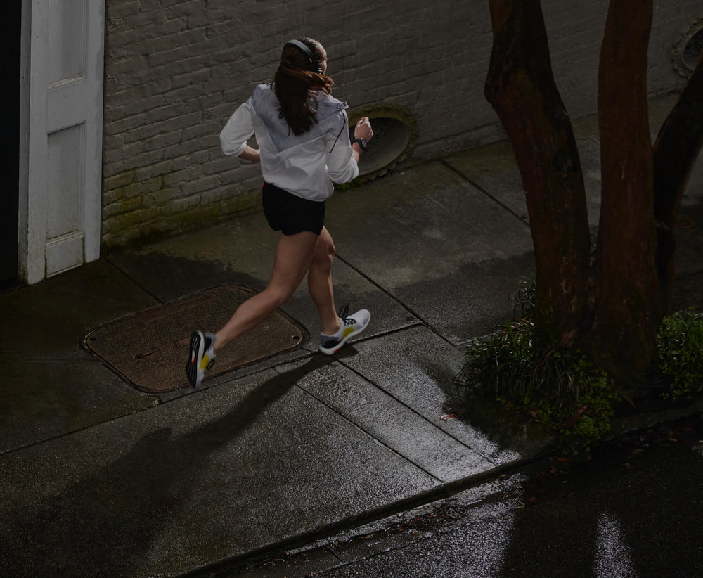 woman jogging at night in shorts and white hoodie 