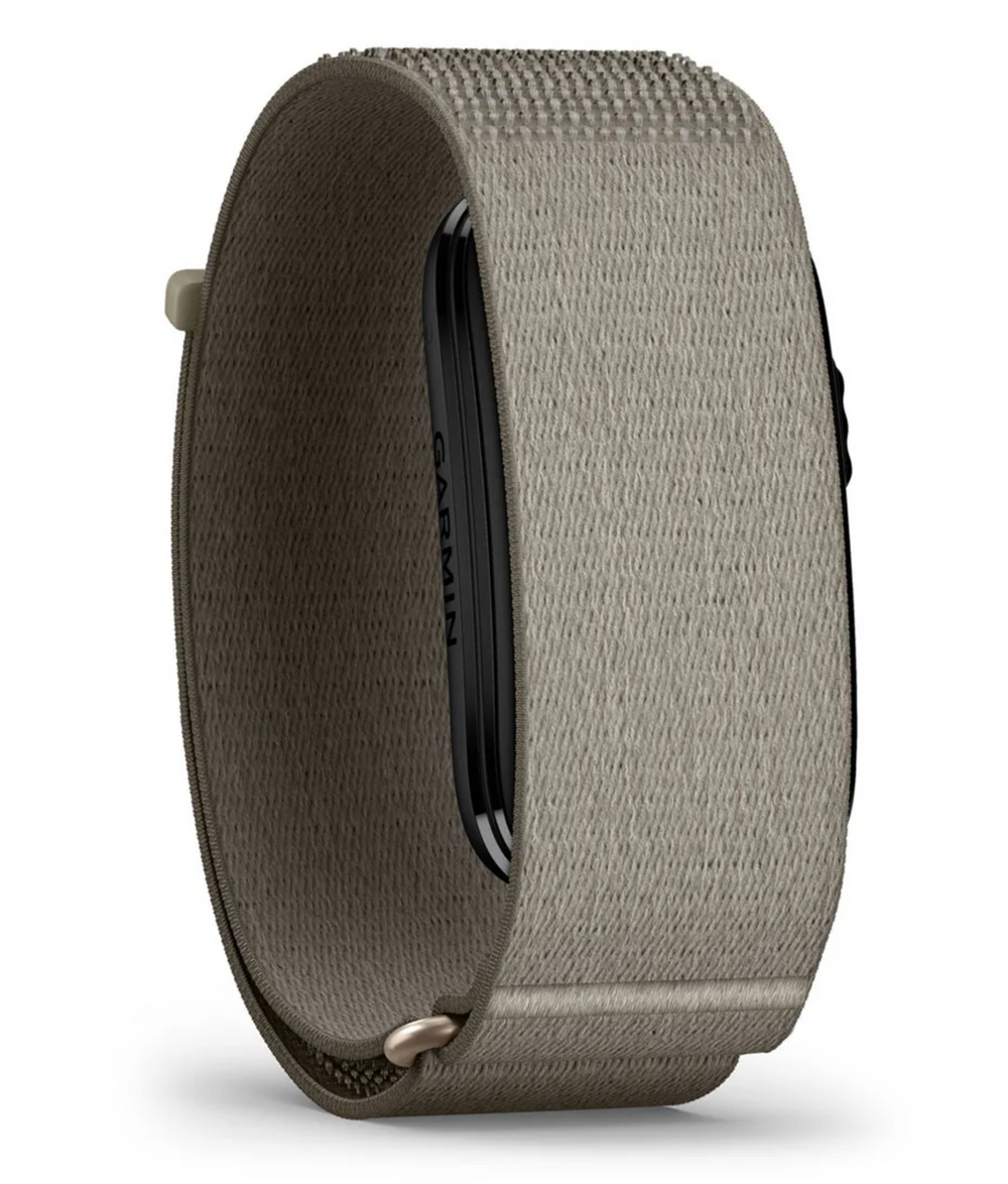 A close-up of a Garmin smartwatch band in a textured taupe-gray fabric, showing the inner black screen area and the fabric strap details against a white background.