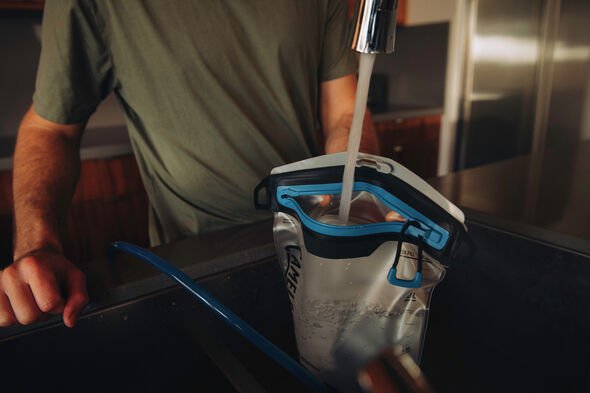 person filling pouch from water faucet 